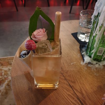 Cocktail designed with flowers, garnish and a bamboo straw